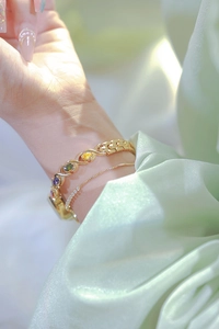 Detail of gold gemstone bracelet featuring colorful oval stones and elegant chain links