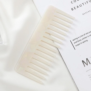 Close-up of a white marble pattern acetate comb on soft white silk fabric