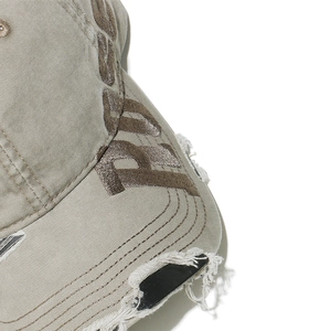 Detailed close-up of 3D embroidery and distressed ripped texture on a khaki canvas cap