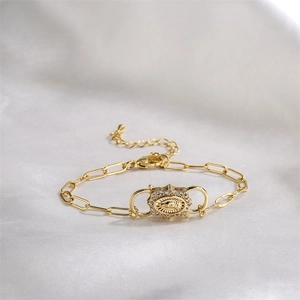 Detail of gold chain bracelet with Our Lady of Guadalupe medallion on white silk