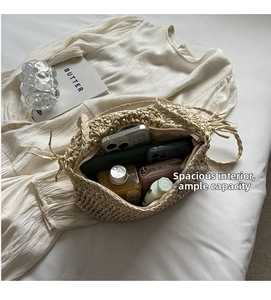 Interior view showing large capacity and zipper closure of the beige woven straw bag