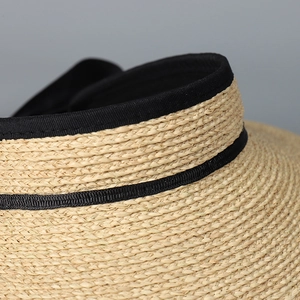 Detailed close-up of woven raffia straw texture and black ribbon trim on sun hat
