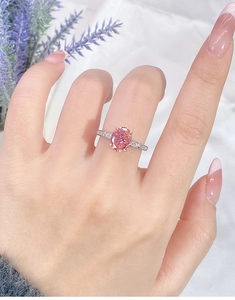 Detail of s925 silver ring with oval pink gemstone and diamonds on a model's hand