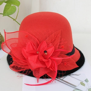 Detailed view of red wool felt hat with mesh veil, floral decor and feather accents