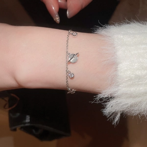 Close-up of silver planet charm bracelet with sparkling zircon stones on a model wrist