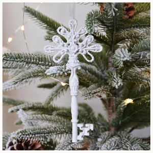 Detail of white vintage resin key ornament with floral carving on a snowy Christmas tree