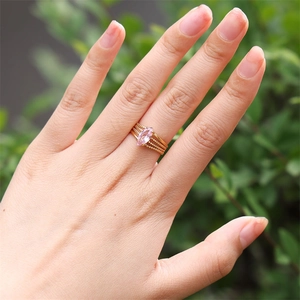 Detailed view of a gold multi-layer ring with pink marquise zircon on a model's finger