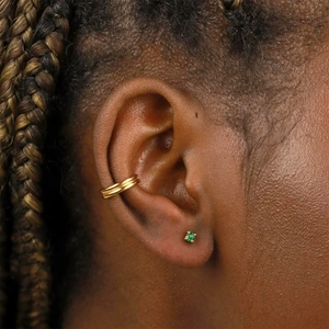 Gros plan d'un ear cuff doré et d'une puce d'oreille avec zircon vert sur le mannequin