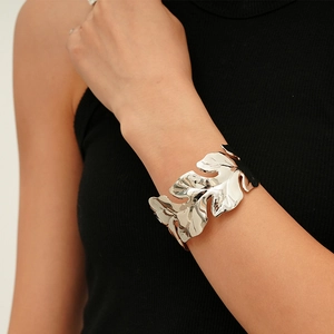 Detail shot of a silver leaf-shaped open cuff bracelet with textured metallic finish