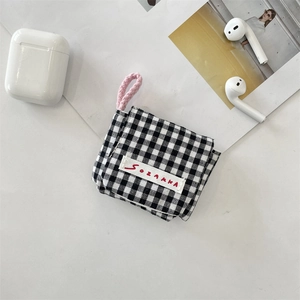 Detalle de una funda de tela para auriculares a cuadros blancos y negros con asa rosa.