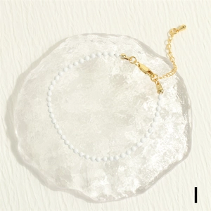 Close-up of white beaded bracelet with gold-plated lobster clasp and adjustable chain