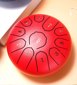 Top view of red steel tongue drum featuring numbered gold musical note scales on textured surface