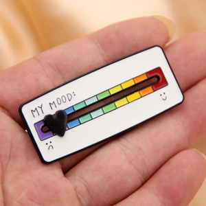 Macro shot of an adjustable mood slider pin showing a rainbow scale and a black heart slider