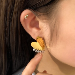 Luxurious gold heart earrings with sparkling crystal tassels on model's ear