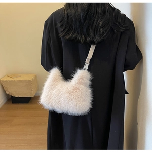 Close-up of a plush faux fur crossbody bag with a slim leather strap and metal hooks