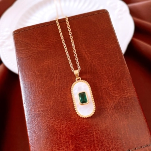 Detail of vintage gold heart pendant with emerald style stone and white shell inlay