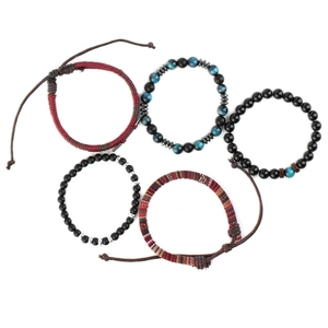 Close-up of five layered bracelets with tiger eye stones, black onyx, and woven leather cords