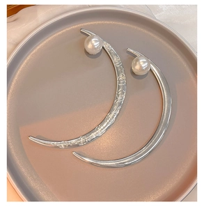 Close-up of crescent hairpins with delicate engraving, smooth metal finish and white pearls