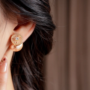 Detail of vintage gold-plated pearl earring with zircon inlays on model's ear
