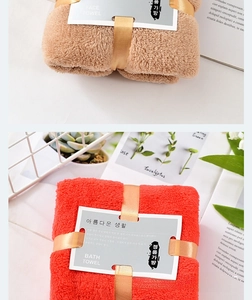 Close-up of thick coral fleece towel set with decorative ribbons and brand cards