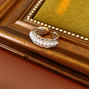 Detail of hollow silver ring with white pearls against vintage dark wood frame