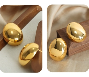 Detail of organic pebble shaped 18k gold plated stud earrings with a mirrored finish
