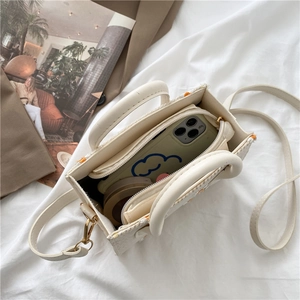 White daisy embroidered canvas handbag with interior compartment on soft bedding