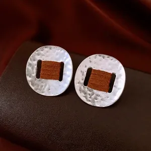 Silver oval hammered metal stud earrings with dark brown cord wrap in luxury style