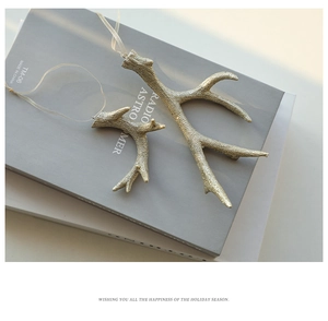 Golden glitter reindeer antler ornaments in two sizes on minimalist books for Christmas