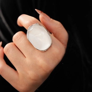 Close-up of a large oval white resin stone ring with a minimalist metal bezel setting