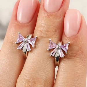 Macro view of silver bow-shaped earrings featuring purple faceted zircon stones