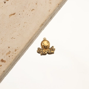 Macro shot of 18K gold plated octopus pendant with black stones on a travertine stone