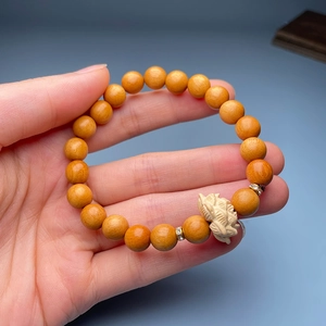 Detail of wooden bracelet with hand-carved lotus bead and metallic spacers on dark background