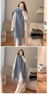 Detail of soft light blue cashmere-feel scarf with long fringes shown in a casual outfit