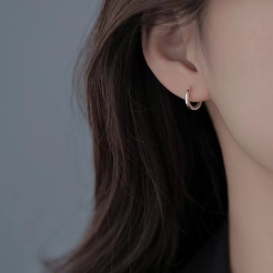 Detailed close-up of polished rose gold hoop earrings worn on a female model earlobe