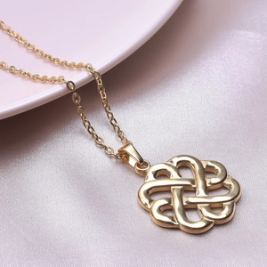 Detailed view of golden 18k plated Celtic knot pendant necklace on pink satin background