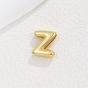 Close-up of gold 10mm DIY letter Z charm for bracelet band on white textured background
