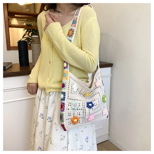 Close-up of handmade crochet flower bag with colorful floral details and knitted strap