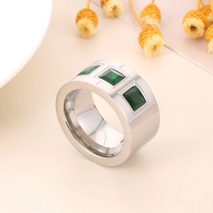 Detailed view of silver wide-band titanium ring with three square green zircon stones