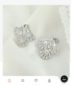 Macro shot of silver pine branch stud earrings on white lace fabric background