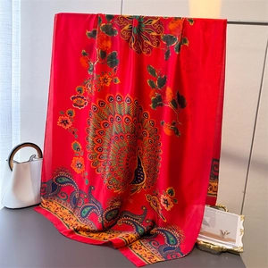 Nahaufnahme eines roten Satinschals mit lebhaften Pfauenfeder- und Paisley-Blumenmustern