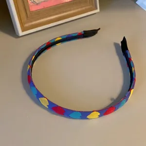 Serre-tête minimaliste en tissu bleu avec motifs de cœurs colorés et embouts protecteurs
