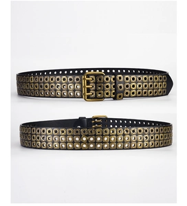 Close-up of punk style belt with triple-prong bronze buckle and metal eyelets