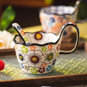 Floral ceramic mug with wave rim, black handle and matching spoon on wooden tray