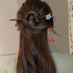 Detail of elegant hair pin with blue floral motif and fringe tassels on bun hairstyle
