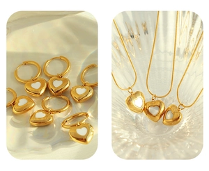 Detail of gold heart necklace and earring set with white shell inlay on reflective surface