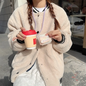 Close-up of beige plush jacket texture with colorful knitted mini storage bag detail