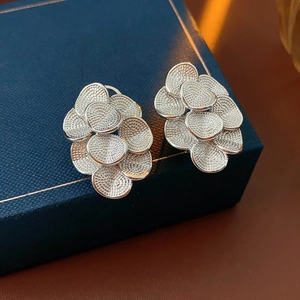 Détail de boucles d'oreilles fleurs argentées texturées sur un coffret à bijoux bleu