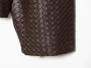 Detailed macro view of deep brown woven leather texture on a cropped jacket collar