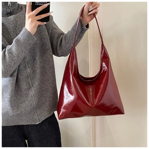 Mirror selfie showing the burgundy glossy faux leather hobo bag on a model shoulder